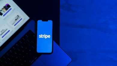 A smartphone displaying the Stripe app placed on a laptop keyboard with a blue monochromatic tone.