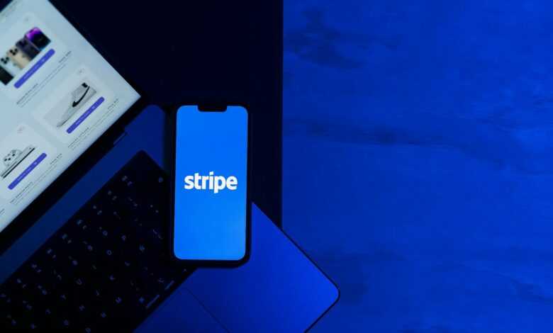 A smartphone displaying the Stripe app placed on a laptop keyboard with a blue monochromatic tone.