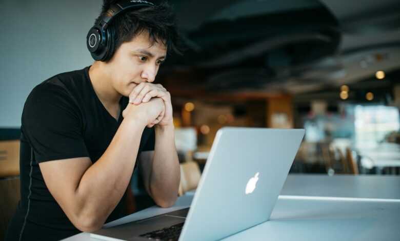 man wearing headphones while sitting on chair in front of MacBook