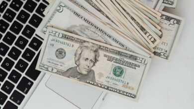 US dollar banknotes scattered over a laptop, symbolizing online finance and digital banking.