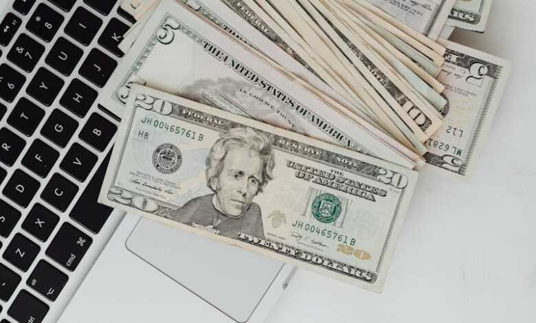 US dollar banknotes scattered over a laptop, symbolizing online finance and digital banking.
