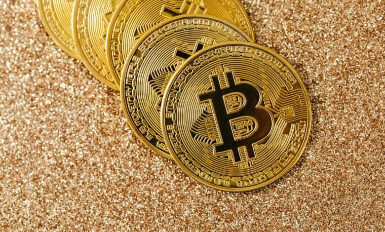 Golden Bitcoin coins arranged on a sparkling glitter surface, symbolizing cryptocurrency and wealth.