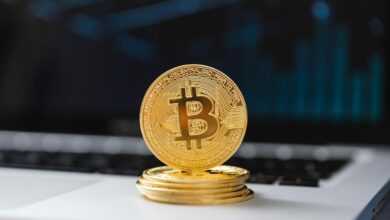 A shiny gold Bitcoin coin on laptop keyboard, symbolizing digital currency and blockchain technology.