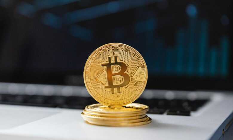 A shiny gold Bitcoin coin on laptop keyboard, symbolizing digital currency and blockchain technology.