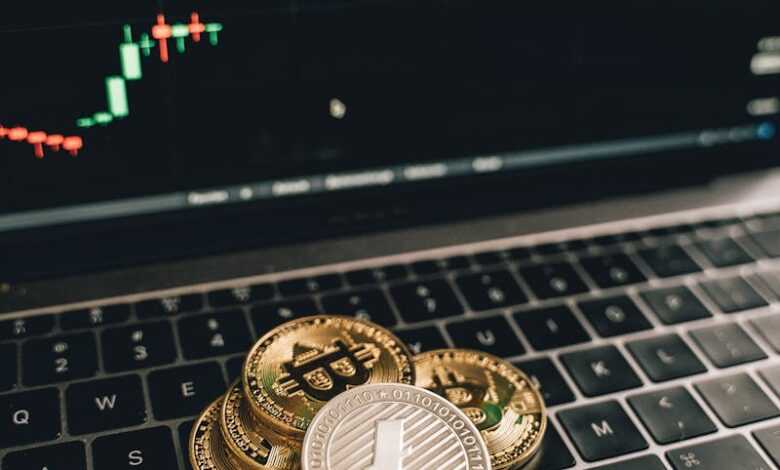 Golden Bitcoin and Litecoin coins on a laptop keyboard with a market graph in Berlin.