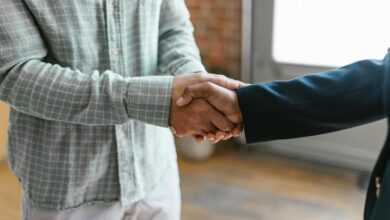 Close-up of two business professionals shaking hands in a modern office environment.