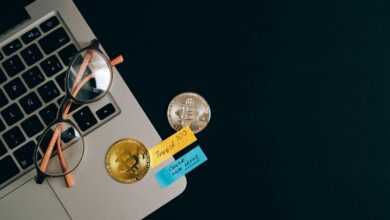 Laptop, bitcoins, and notes on a desk representing cryptocurrency investment concept.