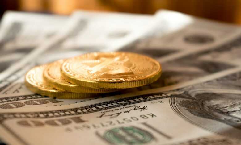 three round gold-colored coins on 100 US dollar banknotes