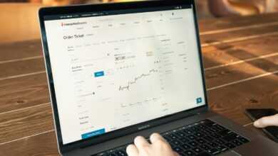 person using macbook pro on brown wooden table