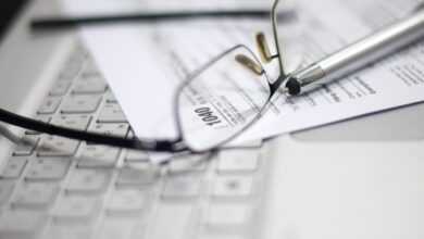 Glasses and pen on tax form and laptop.