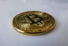 a gold bit coin sitting on top of a white table