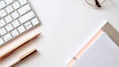 pen near black lined paper and eyeglasses