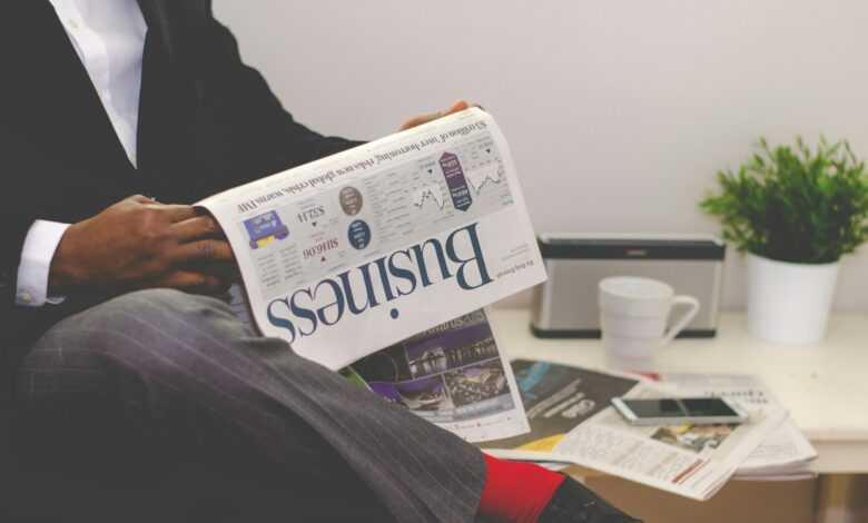 person sitting near table holding newspaper