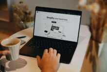 A person sitting at a table using a laptop computer