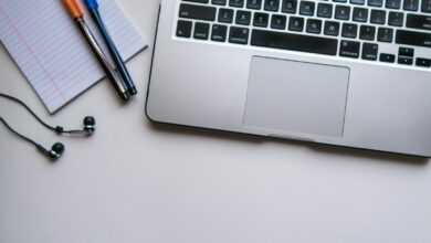 silver laptop computer beside white ruled paper